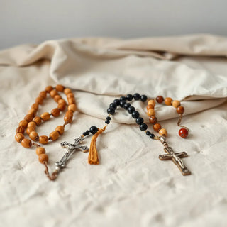 Assorted rosaries with different bead materials and small crucifixes laid neatly on neutral fabric