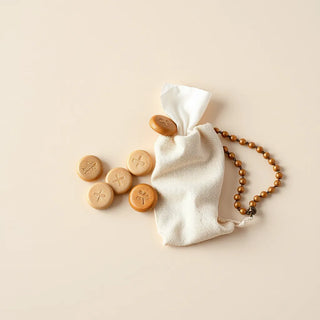 Prayer tokens with a rosary chain and small fabric pouch on a neutral background