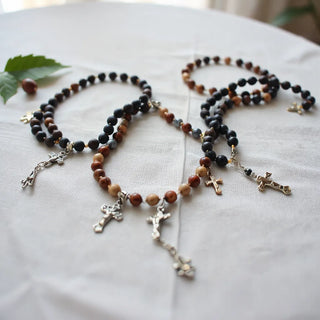 Rosary bracelets with small crucifixes and bead strands arranged on light fabric