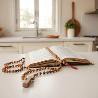 Wooden rosary laid beside an open prayer book with soft natural light