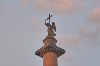 a statue of an angel holding a cross on top of a building