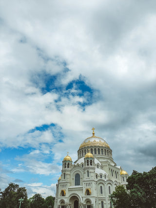 A large white building with gold domes under a cloudy sky