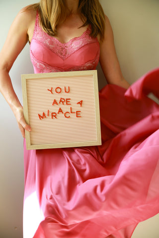 Woman holds sign that says you are a miracle.